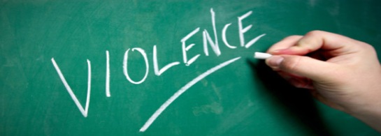 Photo of a hand writing the word "violence" on a chalkboard